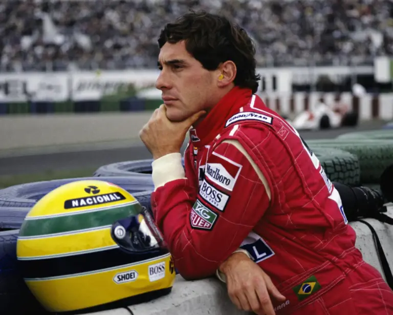 Senna, le casque enlevé à côté de lui qui observe la piste
