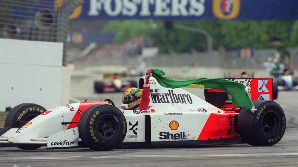 senna dans sa mclaren tenant le drapeau du brésil dans ses mains